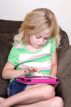 Child or preschooler using a tablet while sitting on couchの写真素材