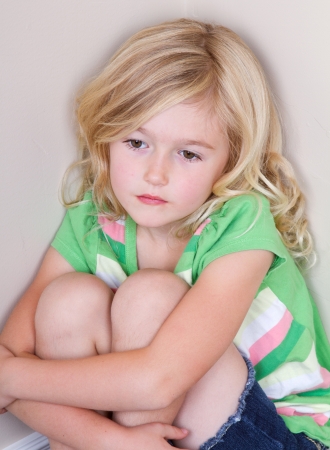 Young child or preschooler sitting in corner, with a sad look on faceの写真素材