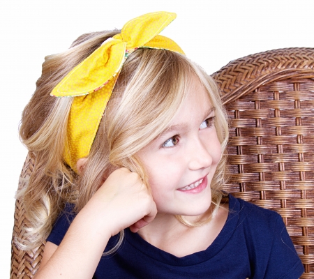 little girl sitting in chair with a happy look on her face, isolated on white backgroundの写真素材