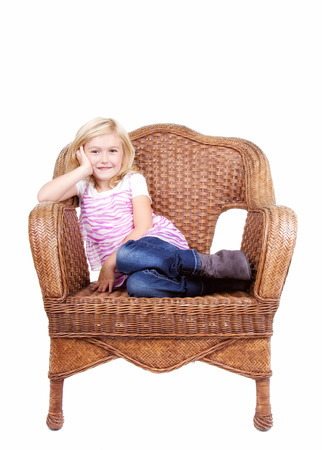 little girl sitting in chair with a happy look on her face, isolated on white backgroundの写真素材