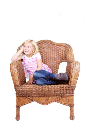 little girl sitting in chair with a happy look on her face, isolated on white backgroundの写真素材
