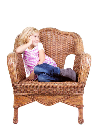 little girl sitting in chair with a happy look on her face, isolated on white backgroundの写真素材