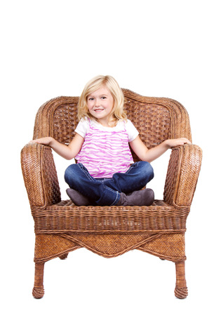 little girl sitting in chair with a happy look on her face, isolated on white backgroundの写真素材