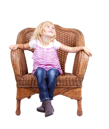 little girl sitting in chair with a happy look on her face, isolated on white backgroundの写真素材
