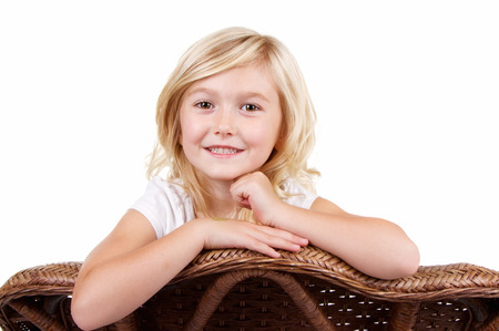 little girl sitting in chair with a happy look on her face, isolated on white backgroundの写真素材