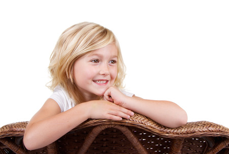 little girl sitting in chair with a happy look on her face, isolated on white backgroundの写真素材