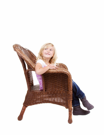 little girl sitting in chair with a happy look on her face, isolated on white backgroundの写真素材