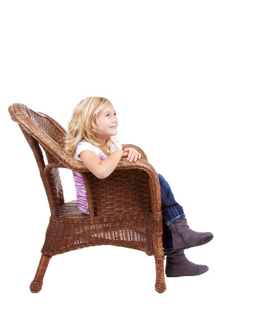 little girl sitting in chair with a happy look on her face, isolated on white backgroundの写真素材