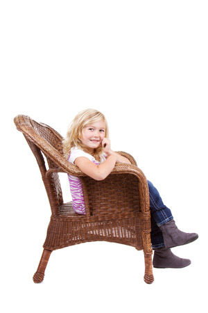 little girl sitting in chair with a happy look on her face, isolated on white backgroundの写真素材
