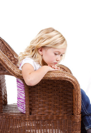 Little girl sitting in chair with a sad or lonely look on her face, isolated on white background.の写真素材