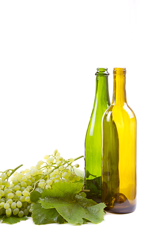 grapes on vine with leaves and empty wine bottles on white backgroundの写真素材
