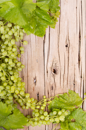 grapes on vine with leaves sitting on rustic wooden plankの写真素材