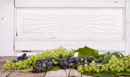 grapes on vine with leaves sitting on rustic wooden plankの写真素材