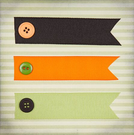 Halloween colored ribbon tags with sewing buttons on paper background for copy spaceの写真素材