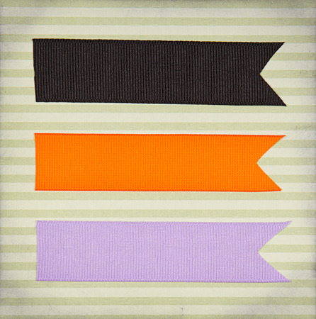 Halloween colored ribbon tags on a scrapbook paper backgroundの写真素材