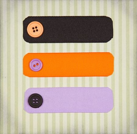 Halloween colored ribbon tags with sewing buttons on paper background for copy spaceの写真素材