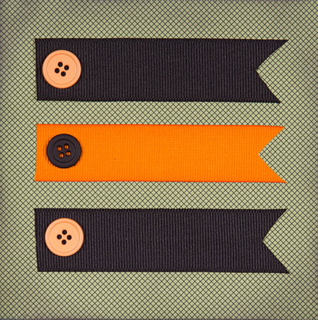 Halloween colored ribbon tags with sewing buttons on paper background for copy spaceの写真素材