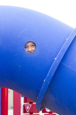 Child playing on playground outside with face showing through a small holeの写真素材