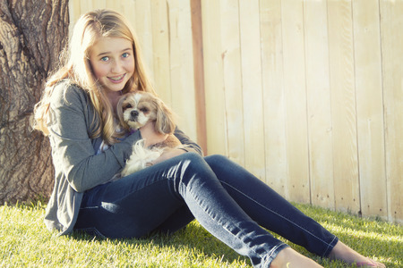 Teenage girl holding a small dog in an outdoor settingの写真素材