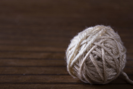 Ball of cream yarn on brown wooden backgroundの写真素材