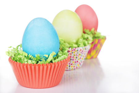 Dyed Easter eggs in a nest of green grass confetti and cup cake wrappersの写真素材