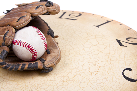 A baseball and mitt on an old vintage clock on an isolated white backgroundの写真素材