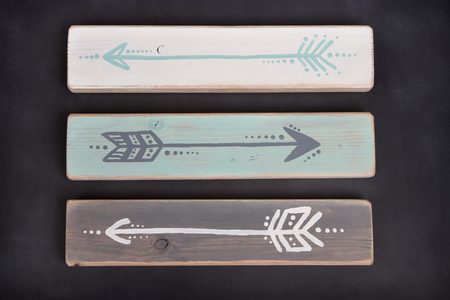 Three hand painted arrows on a wooden plank on a blackboard backgroundの写真素材