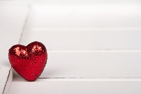 Red glitter heart on a white wooden backgroundの写真素材