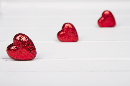 Red glitter hearts on a white wooden backgroundの写真素材