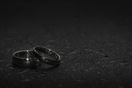 Silver Wedding Rings on a rock background with water dropletsの写真素材