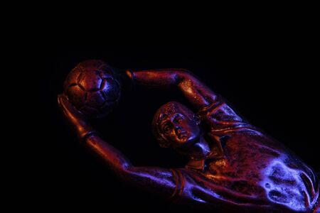 A trophy of a football (soccer) goalkeeper lit by red and blue flashes ideal for a presentation ceremonyの写真素材