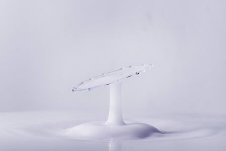 A macro photo of two drops of blue food coloring in a pool of thick creamy milk captured using a flash to freeze the motionの写真素材