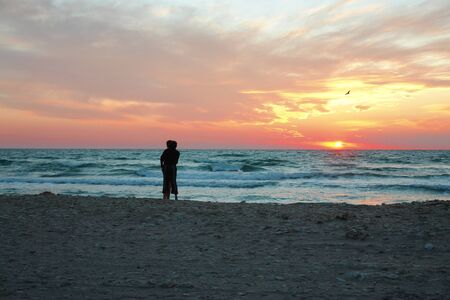 Pair of lovers standing on a beach during a sunsetの写真素材