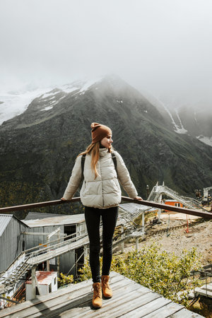 Girl traveler with backpack enjoy mountain nature standing on wooden bridge. Concept of freedom,...