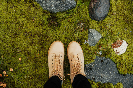 <p>Selfie of woman's legs in brown trekking boots standing on mossy ground</p>の写真素材
