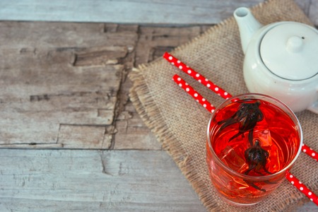 Red herbal rosella tea in cup and teapot on the wooden vintage table.の写真素材