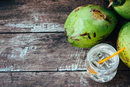 Fresh coconut juice in the jar and ripe coconuts on the vintage wooden table. Organic food concept....