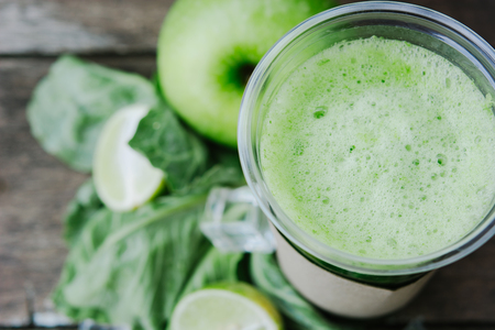 Green apple smoothie in glass and kale leaves on rustic wooden table. Detox shake background with copy space. Healthy drink recepie.の写真素材