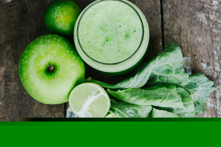 Green apple smoothie in glass and kale leaves on wooden tableの写真素材
