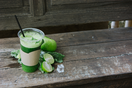 Green apple smoothie in glass and kale leaves on rustic wooden table. Summer Detox shake background with copy space. Healthy drink recepie.の写真素材