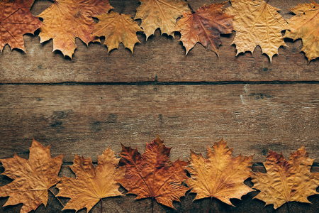 Autumn leaves on rustic wooden background. Top view with copy space. Wallpaper for Halloween party and seasonal rural festival.の写真素材