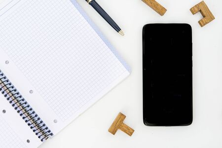 Pen, notepad and mobil with wooden puzzle pieces on white backgroundの写真素材