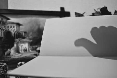 Shadow and reflection on the book of OKAY sign made by hand. Black and white.