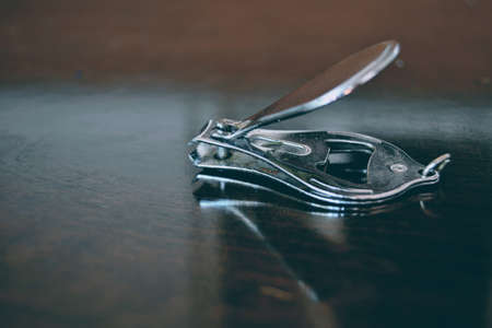 Close up nail cutter on the wooden table. Nail cutter made of metal and coated by shiny layer on the...
