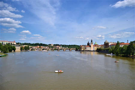 Brown Vltava River and blue sky in Prague, Czech Republic. Peoples swimming by means of a boats on...