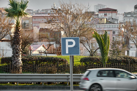 Selective focus photo, Parking sign on blue ground and blurred and motion of a car.の写真素材