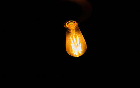 Ancient lamp, tungsten and vintage retro lamp, black isolated background. Idea development concept ideas.の写真素材