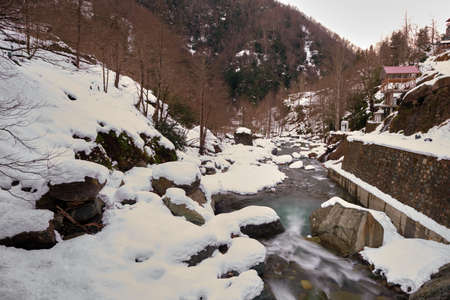 River at winter season, long exposure river water flow and snow river on hill.