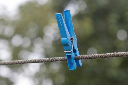 Blue clothespin on rope with blur background, close-up.