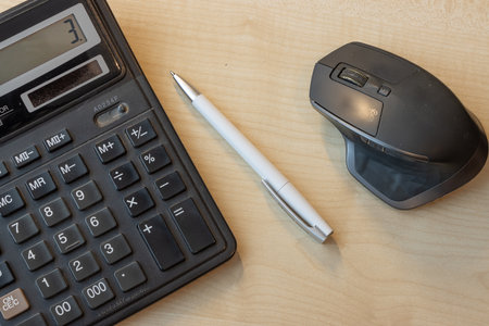 calculator, mouse and pen on the wooden table, business concept
